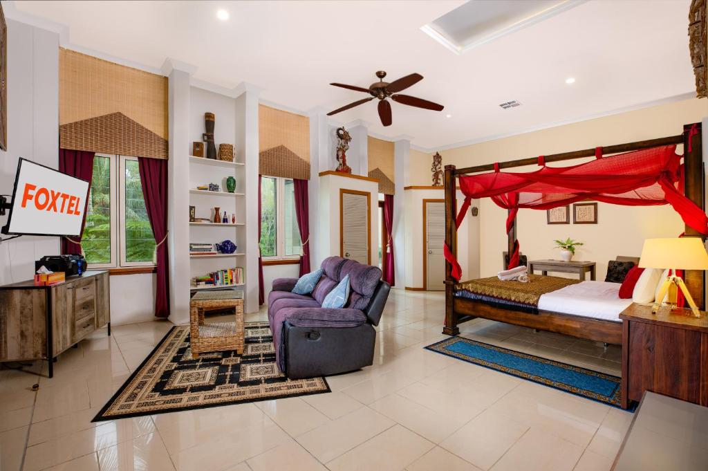 um quarto com uma cama de dossel e um sofá em LUXURY Apartment Studio PORT DOUGLAS 65 SQ MTRS and Bath em Port Douglas