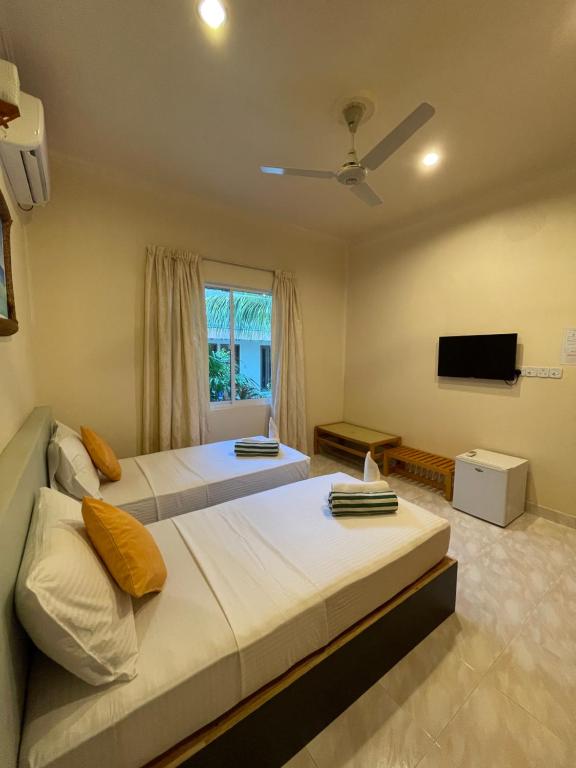 Thoddoo Retreat Grand في ثودو: سريرين في غرفة مع تلفزيون