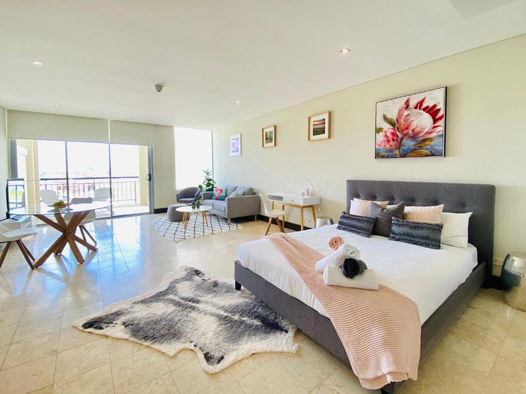 a bedroom with a large bed and a living room at 237 Santai - Second floor studio by uHoliday in Casuarina