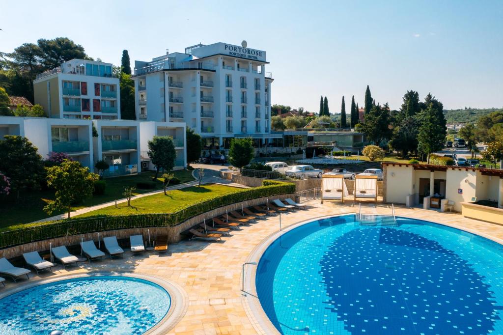 Blick auf einen Pool mit Stühlen und ein Gebäude in der Unterkunft Boutique Hotel Portorose in Portorož