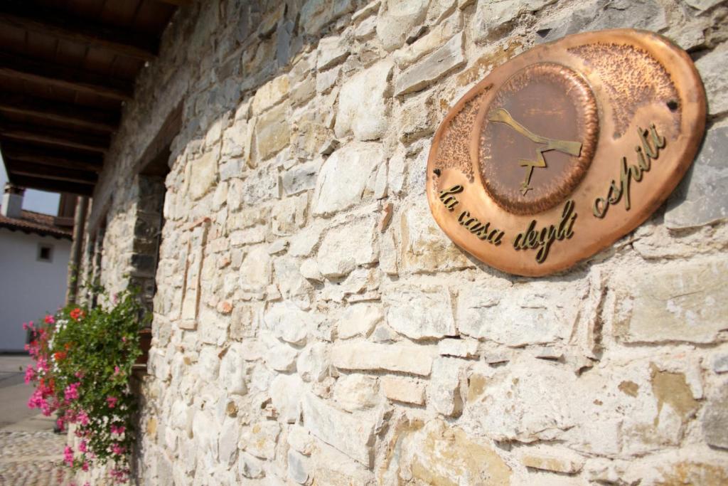 un reloj a un lado de una pared de piedra en Agriturismo La Casa Degli Ospiti, en Dolegna del Collio