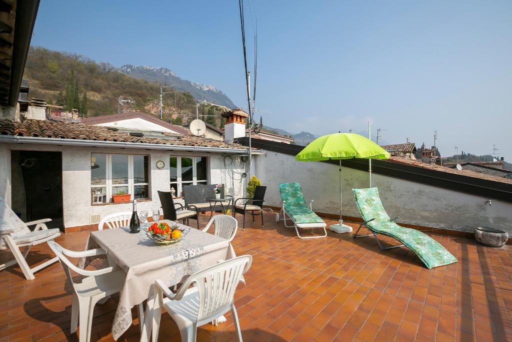 a patio with a table and chairs and an umbrella at Casa Angela -beautiful View lake - Happy Rentals in Toscolano Maderno