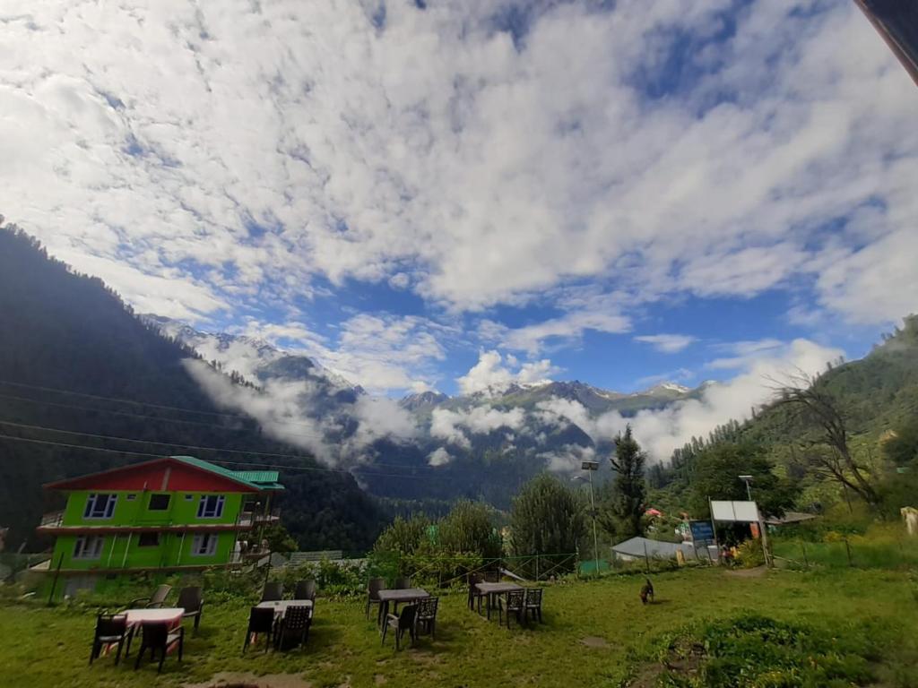 a view of a field with tables and a house at Shiva mountain guest house & Cafe in Tosh