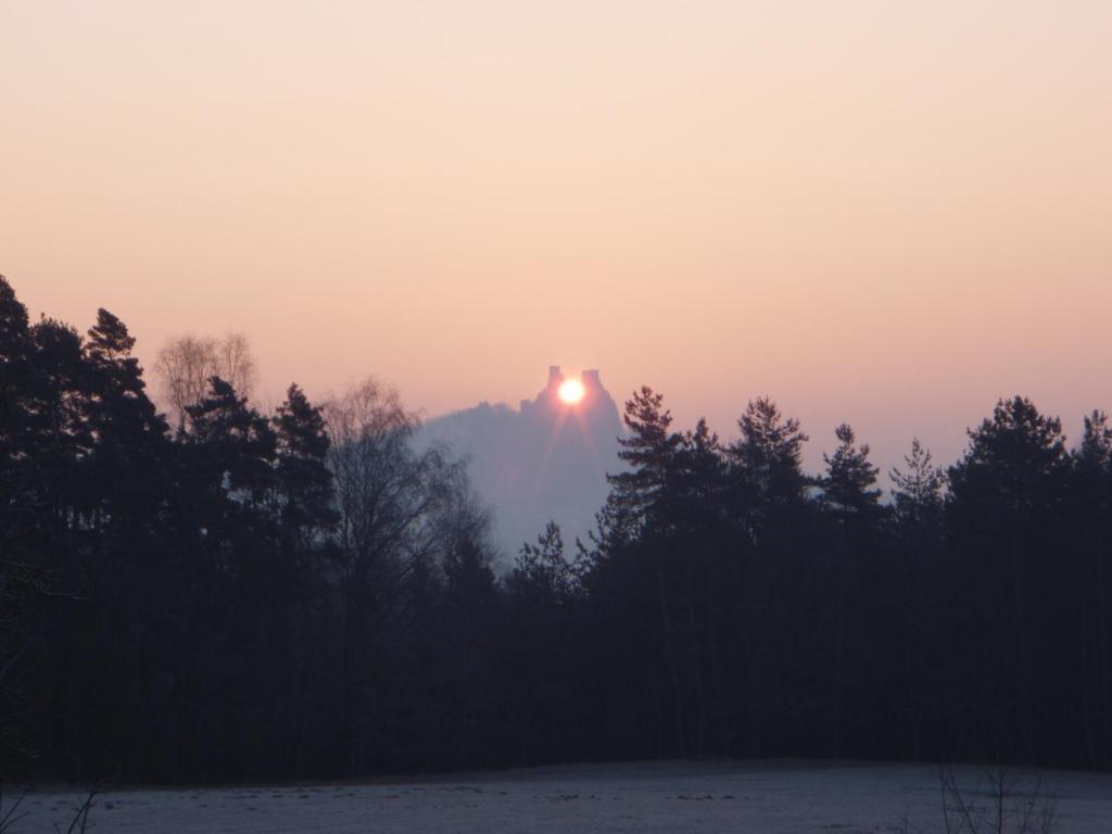 a sunrise over a mountain with trees in the foreground at Pension Stará Škola in Hrubá Skála