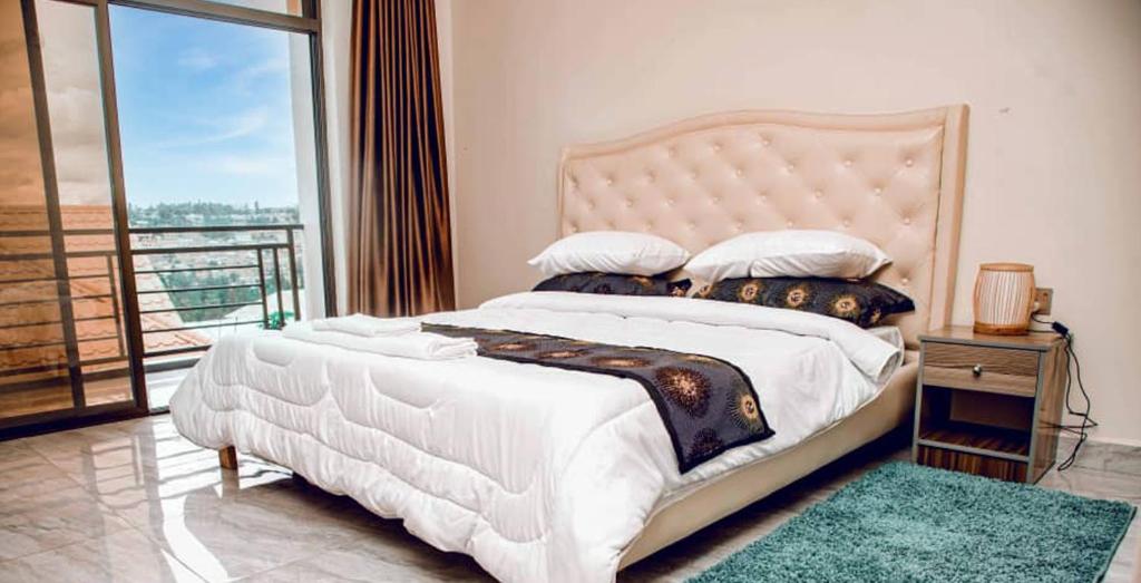 a bedroom with a large white bed and a balcony at Nziza View Hotel in Kigali