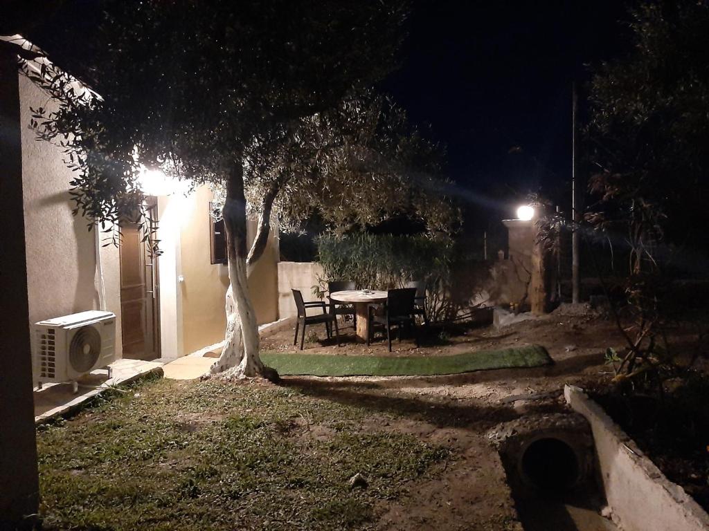 un patio trasero por la noche con una mesa y un árbol en Terezina wood house, en Kanakádes