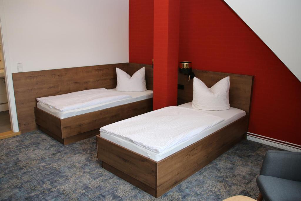 two beds in a room with a red wall at Pension zum Kleistpark in Frankfurt Oder