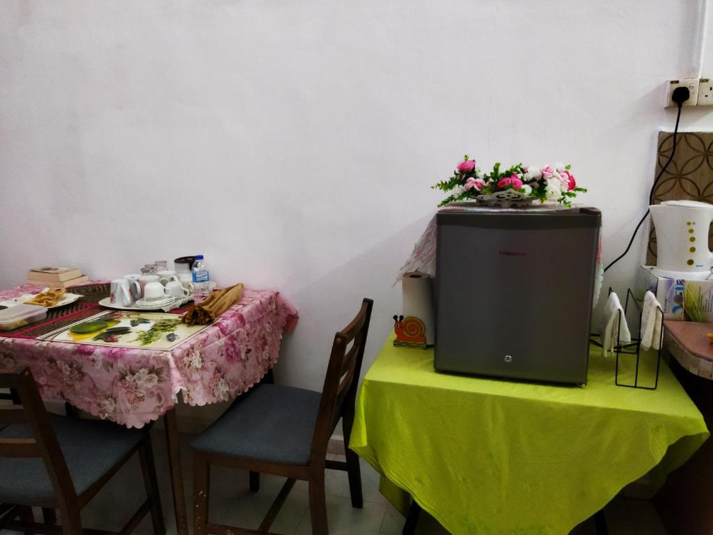 HOMESTAY UMI KODIANG في Kodiang: غرفة بها طاولتين وطاولة عليها زهور