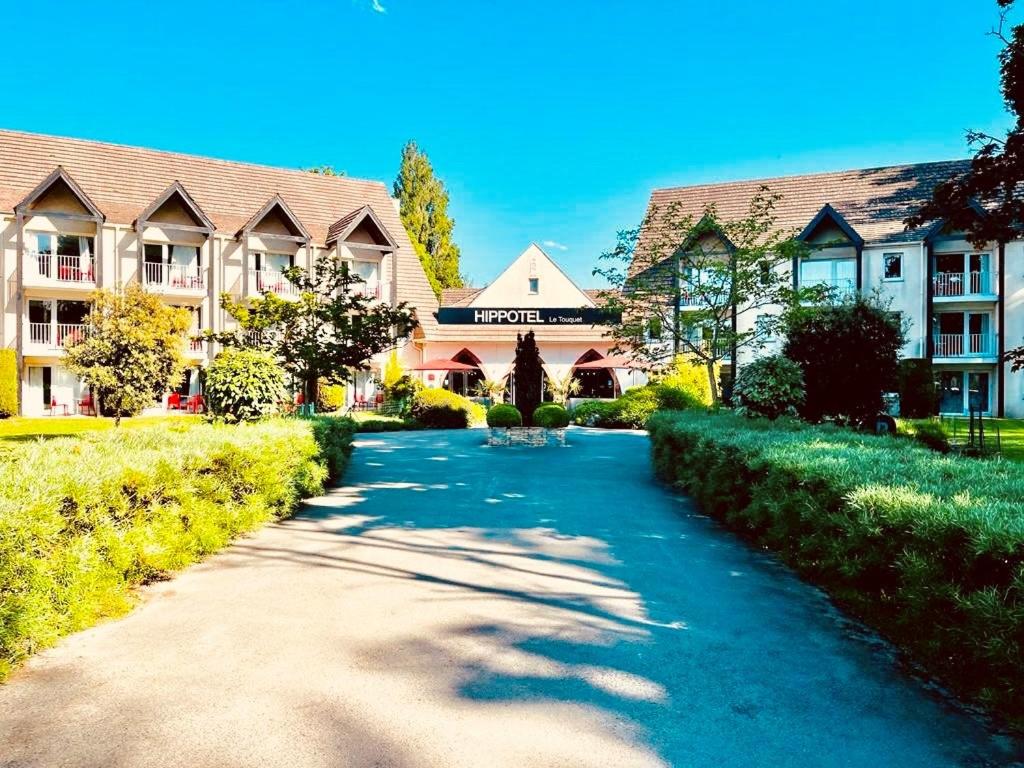 un chemin traversant un complexe avec des bâtiments et des arbres dans l'établissement Hippotel, à Le Touquet-Paris-Plage