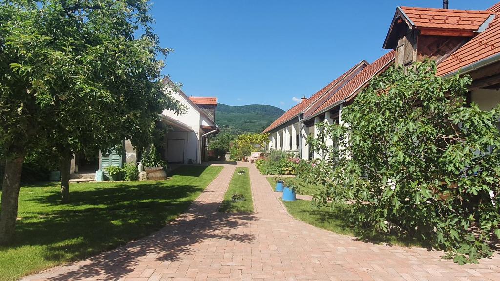 eine Backsteinstraße, die zu einem Gebäude mit Bäumen führt in der Unterkunft Mayday Cottage in Pócsmegyer