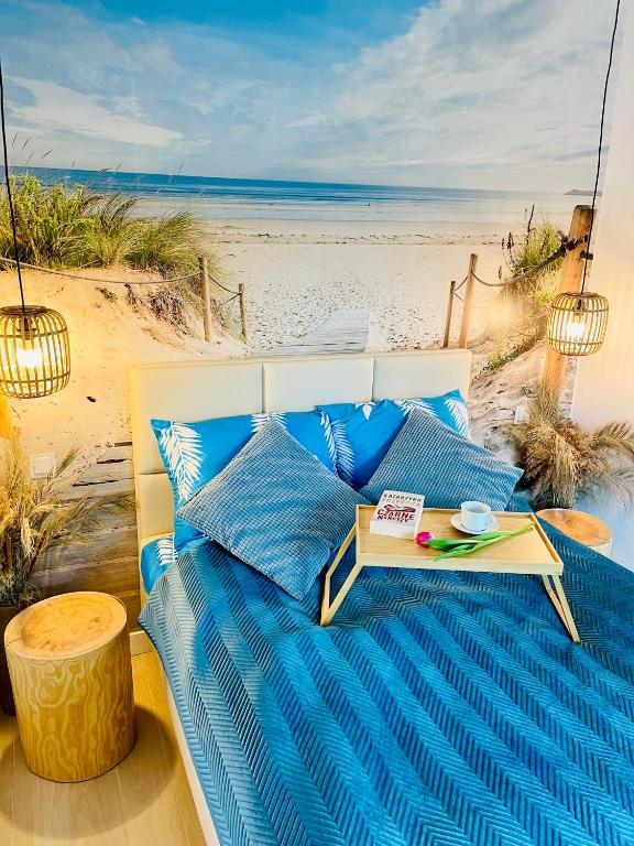 łóżko z niebieskimi poduszkami i stołem na plaży w obiekcie Apartament Baltic A8 Pobierowo w Pobierowie