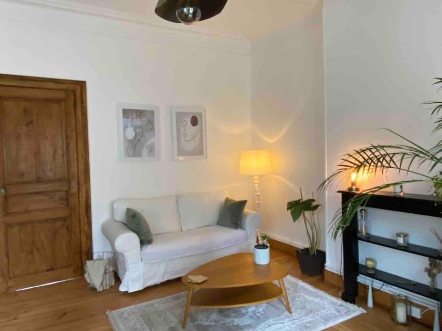 uma sala de estar com um sofá branco e uma mesa em Appartement VH III em Le Mans