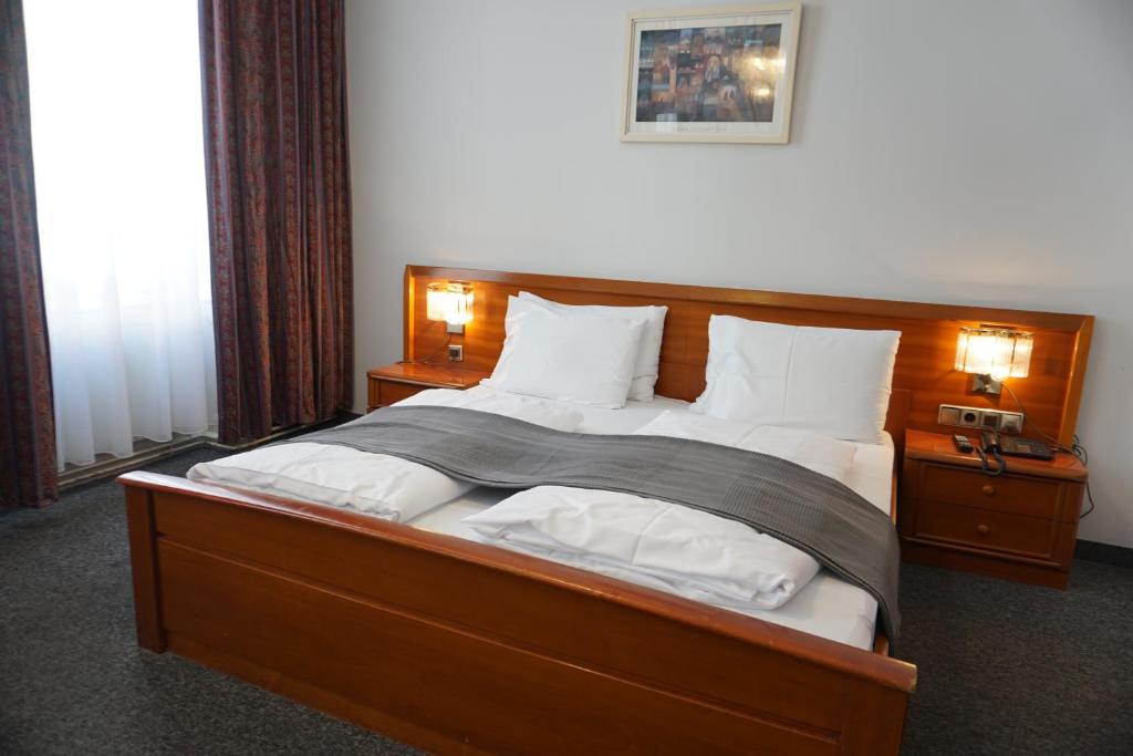 Un dormitorio con una gran cama de madera con almohadas blancas. en Hotel Pension Lumes - Self Check In, en Viena