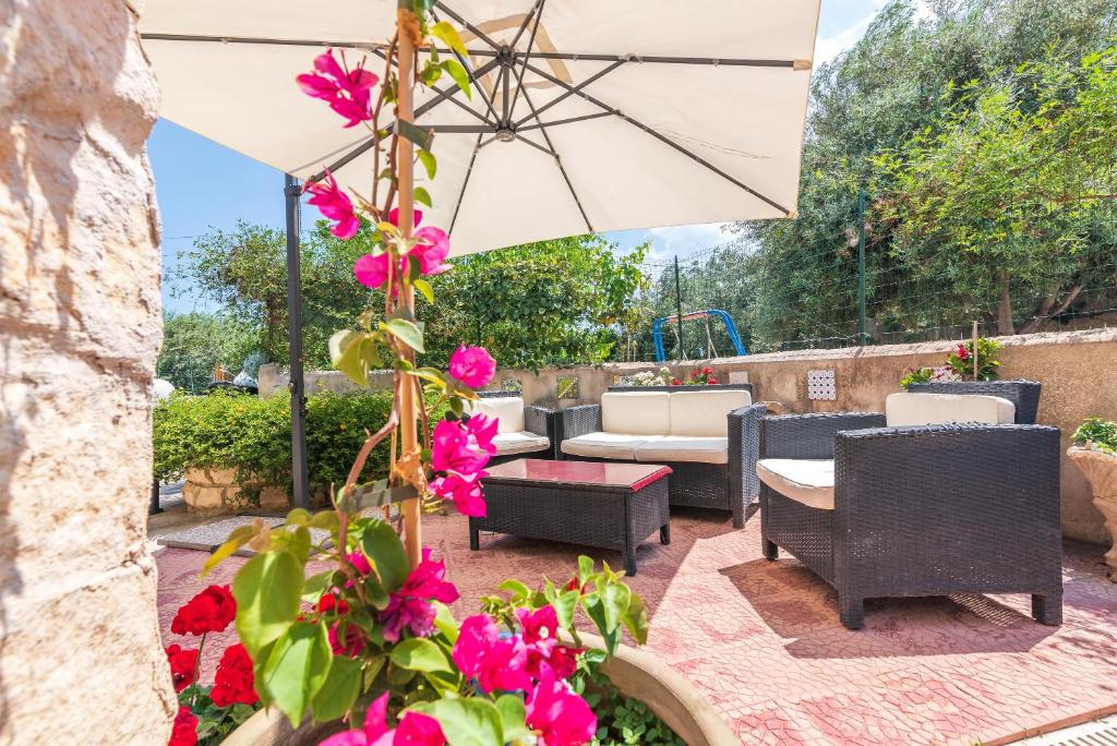 un patio con flores rosas y una sombrilla en Casale siculo, en Avola