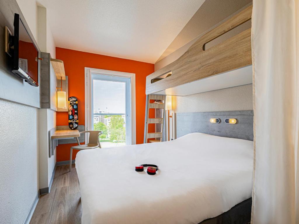 ein Hotelzimmer mit einem weißen Bett und orangefarbenen Wänden in der Unterkunft ibis budget Paris Porte d'Italie Ouest in Le Kremlin-Bicêtre