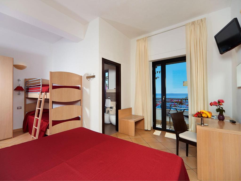 a bedroom with a red bed and a view of the ocean at Hotel Cala Luna in Cala Gonone