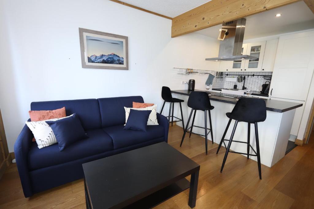 ein Wohnzimmer mit einem blauen Sofa und einer Küche in der Unterkunft Le Schuss Tignes, appartement cosy 4 personnes in Tignes