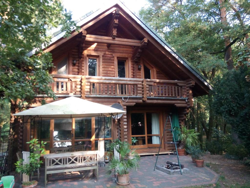 ein Blockhaus mit einem Sonnenschirm davor in der Unterkunft Holzhaus am See in Zernsdorf