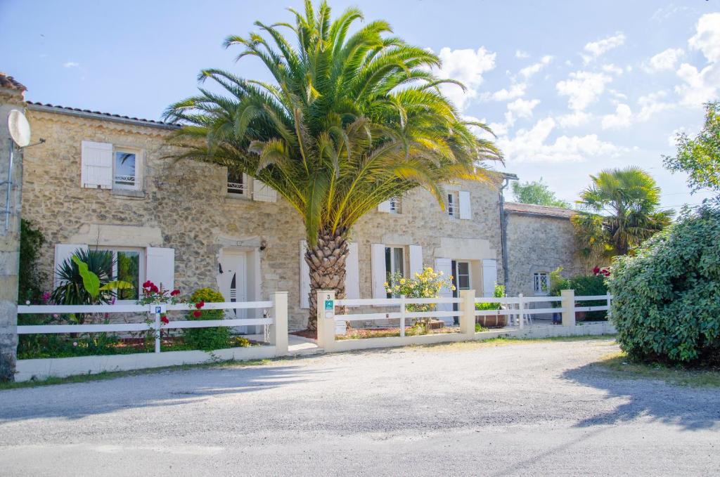 una casa con una palmera y una valla blanca en La Pause Céleste en Ordonnac