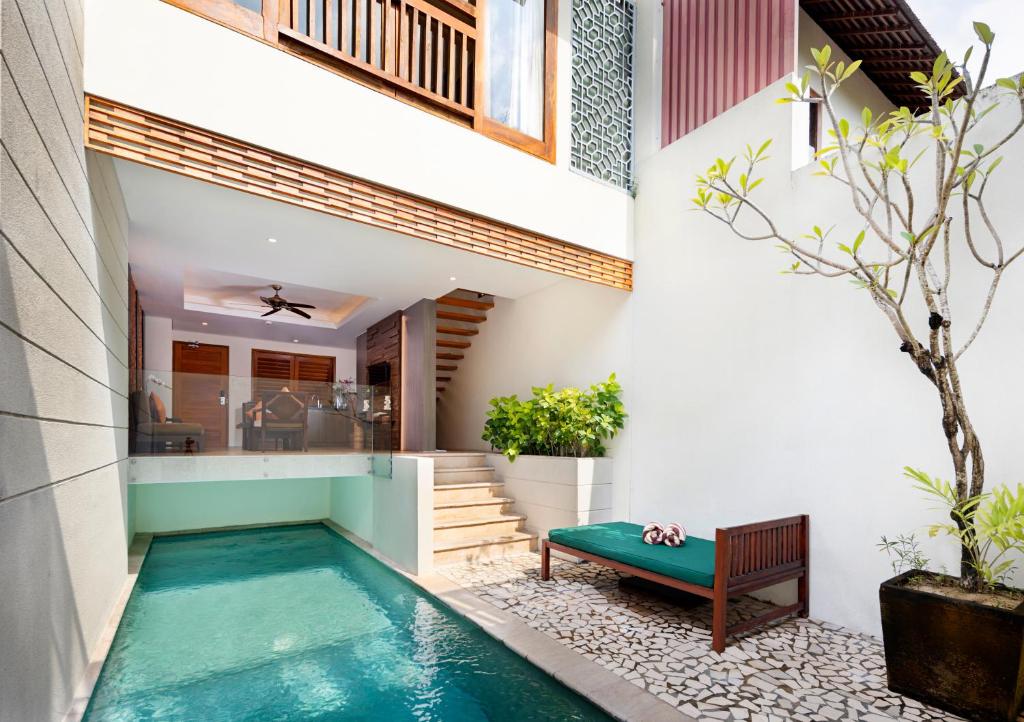 a pool in the middle of a house with a bench at Villa Kayu Raja in Seminyak