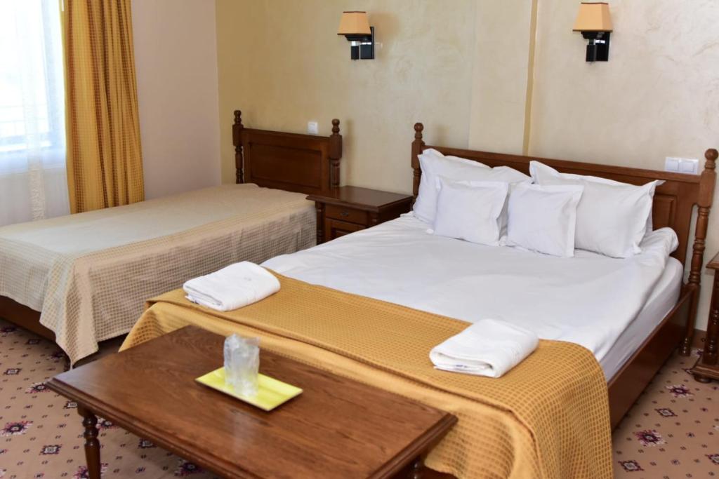 ein Hotelzimmer mit 2 Betten und einem Tisch in der Unterkunft BellaVista Brasov in Săcele