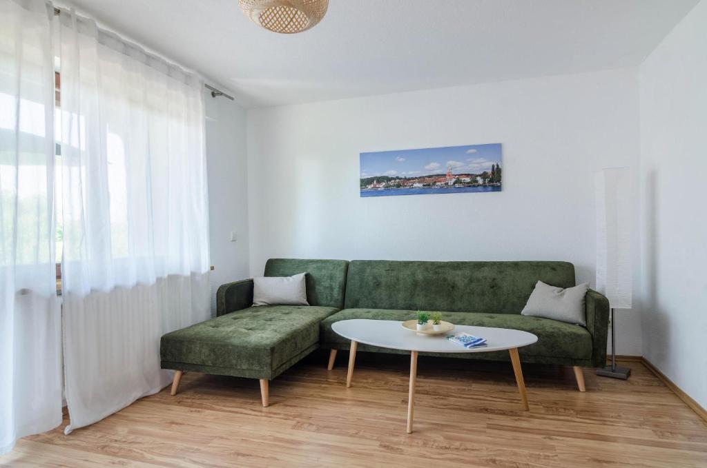 ein Wohnzimmer mit einem grünen Sofa und einem Tisch in der Unterkunft Ferienwohnung zum Hecht in Überlingen