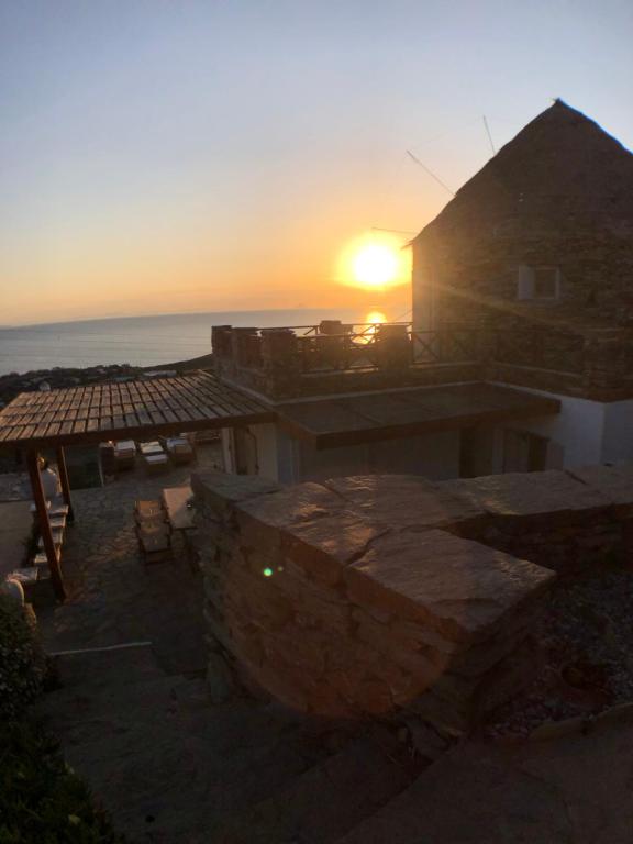 Koundouros的住宿－The Stone Windmill，日落在一座有海洋背景的建筑上