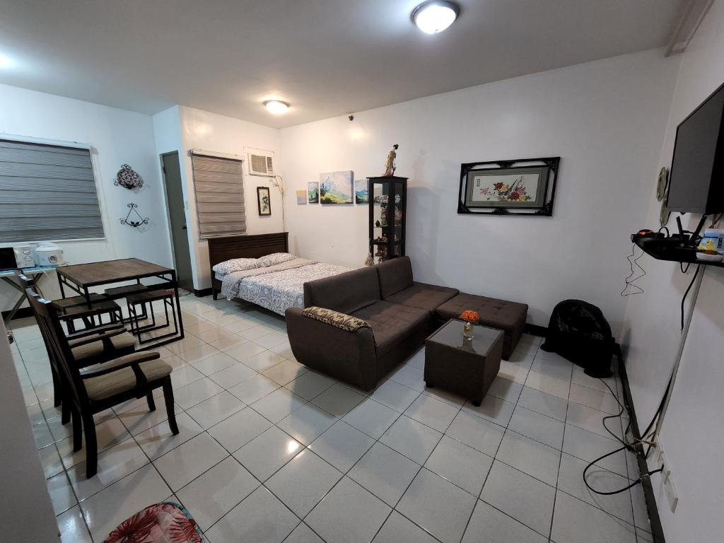 Ilia's Cozy Abode near Enchanted Kingdom & Nuvali في سانتا روزا: غرفة معيشة مع أريكة وسرير