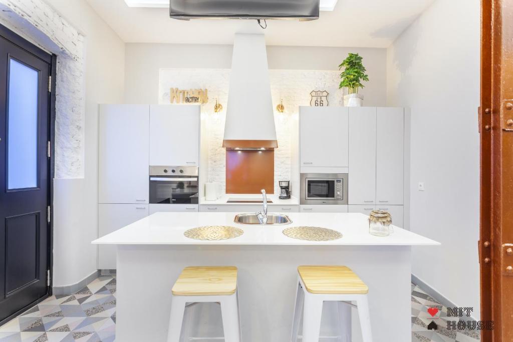 una cocina con armarios blancos, fregadero y taburetes en MIT House Salamanca Studio en Madrid, en Madrid