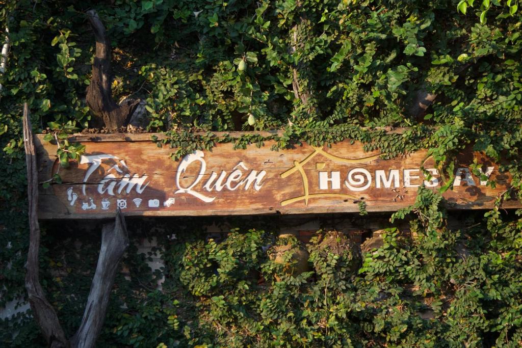 a wooden sign on a wall with vines at Tầm Quên Homestay in Tây Ninh