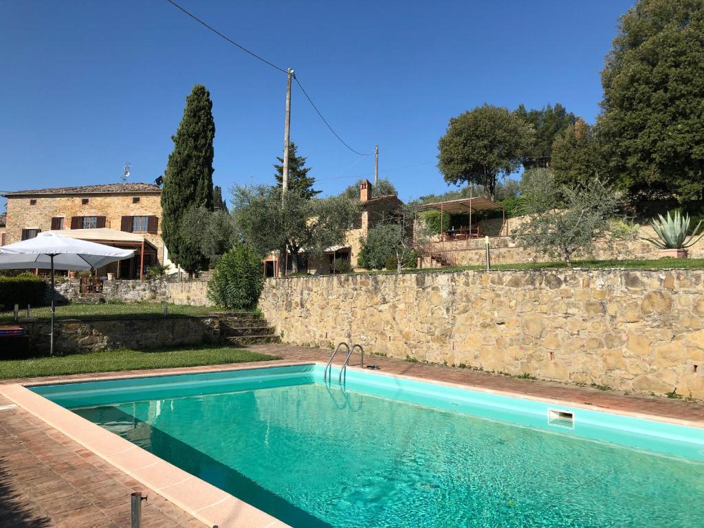 a swimming pool in front of a stone wall at Podere Zelmira in Sinalunga