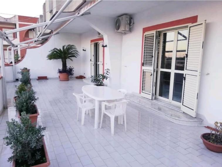 een patio met een witte tafel en stoelen in een gebouw bij House with sea view/Casa con terrazzo vista mare in Siderno Marina