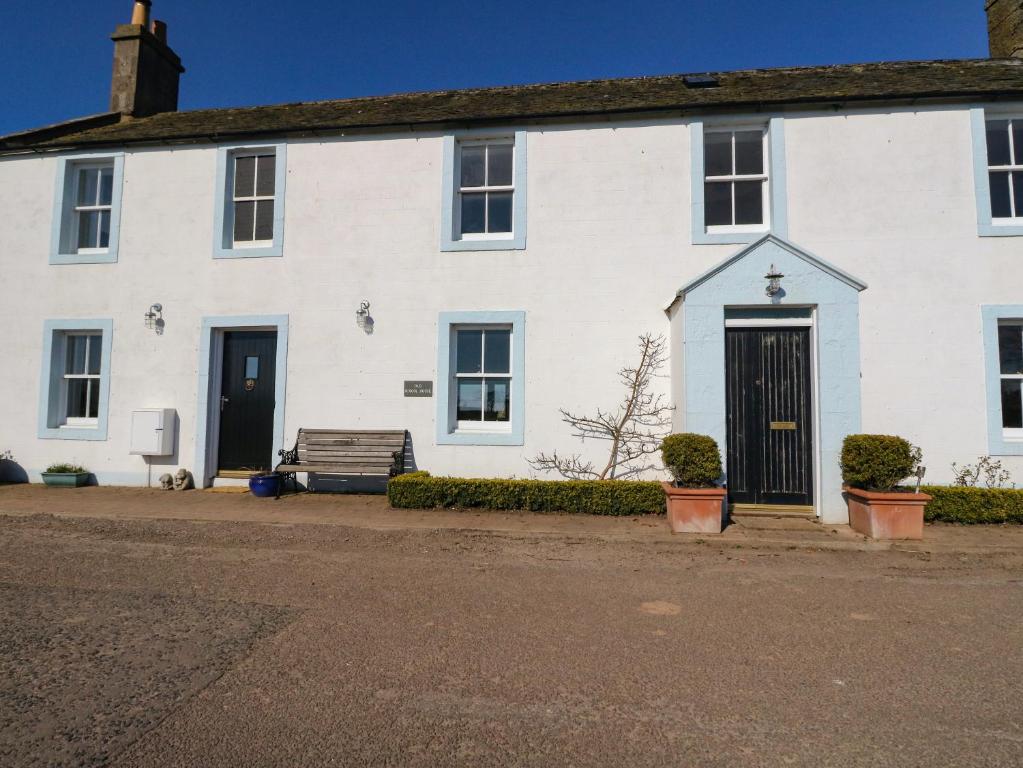 una casa bianca con una panchina davanti di The Old Schoolhouse a Montrose