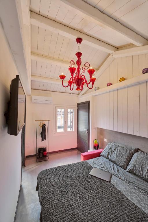 威尼斯的住宿－Simone Cenedese Murano Apartments - Ambra，一间卧室配有一张大床和一个吊灯。