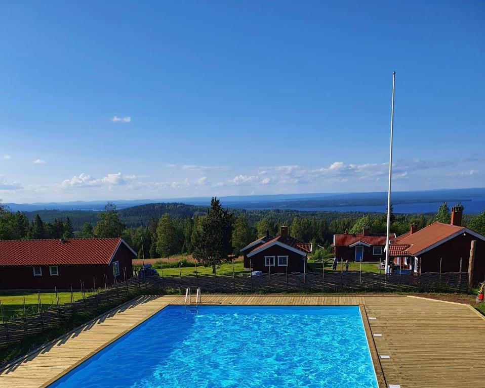 a large blue swimming pool with houses in the background at Åsengården Boende & Gästgiveri in Asen