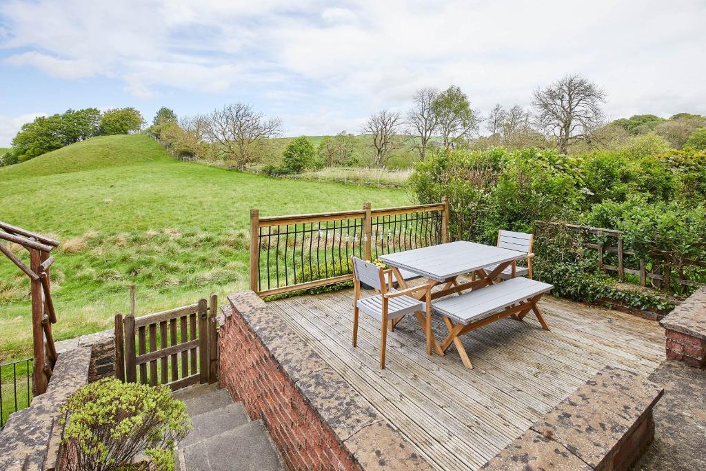 Host & Stay - Ramblers Rest Cottage في Greenhead: سطح خشبي مع طاولة ومقعد