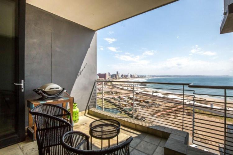 een balkon met 2 stoelen en uitzicht op het strand bij Durban Point Waterfront, 1006 Quayside in Durban