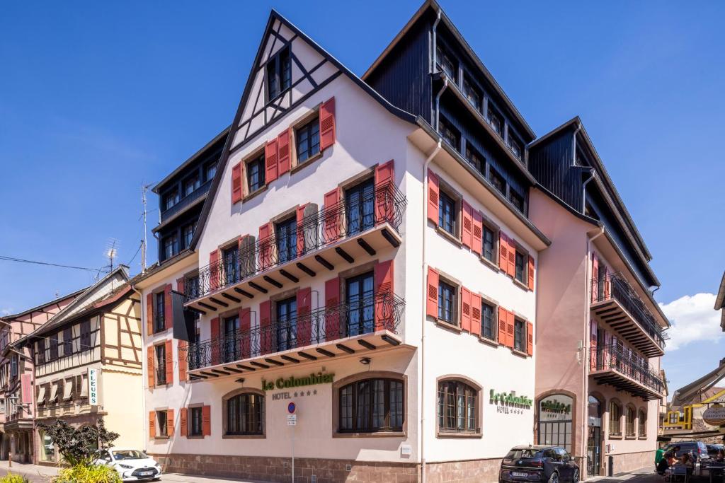 ein weißes Gebäude mit Balkon auf einer Straße in der Unterkunft Hotel Le Colombier in Obernai