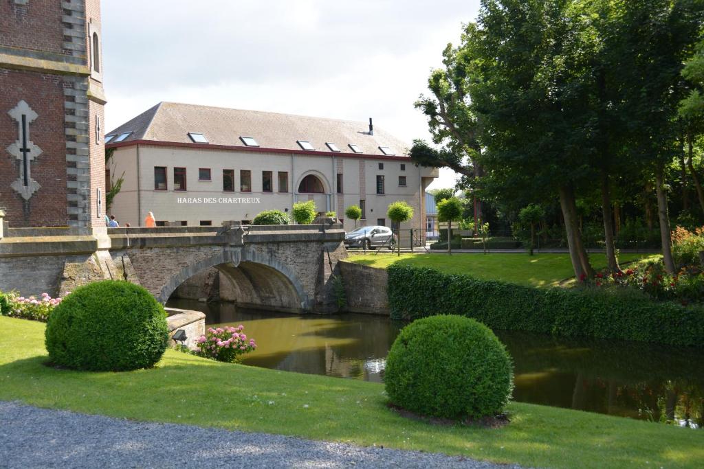 eine Brücke über einen Fluss vor einem Gebäude in der Unterkunft Haras des Chartreux in Estaimbourg