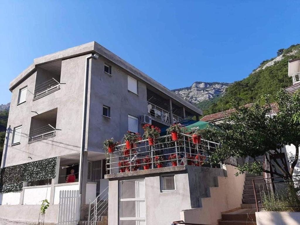 ein Gebäude mit einem Balkon mit Blumen darauf in der Unterkunft Apartmani Momčilović in Čanj