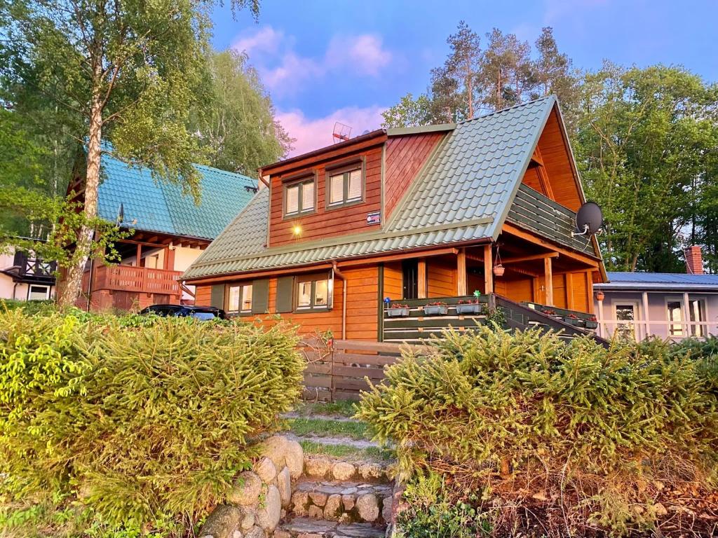 une grande maison en bois avec un toit vert dans l'établissement Domek letniskowy Opowieści z Narie Kretowiny, à Kretowiny