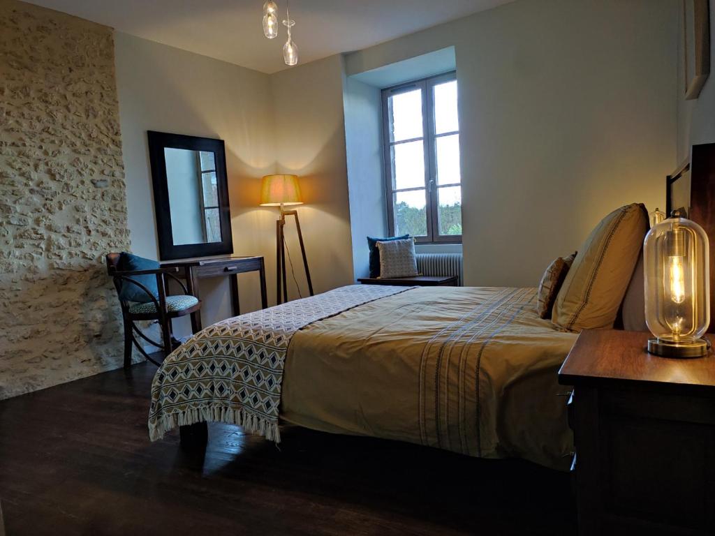 a bedroom with a bed and a table and a mirror at Planches et Plonk in Belvès