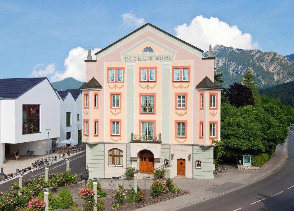 un grande edificio rosa sul lato di una strada di Hotel Hirsch a Füssen