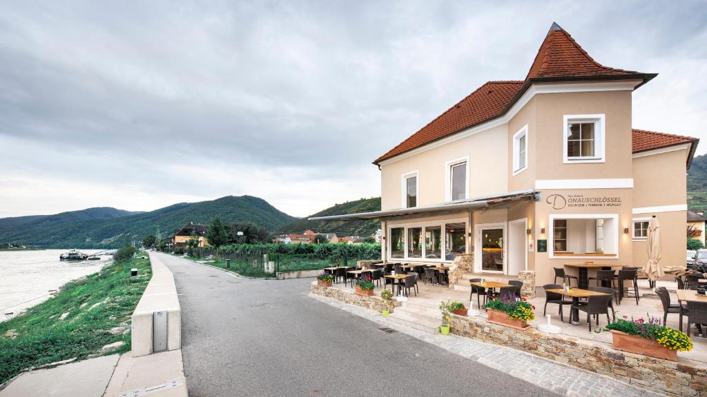 a building with tables and chairs next to a river at Donauschlössel in Spitz