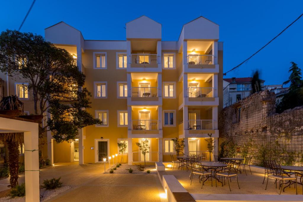 un bâtiment avec des tables et des chaises devant lui dans l'établissement PORTO SERENO apartments, à Šibenik