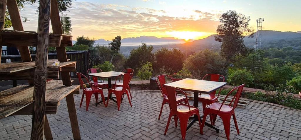 a group of tables and chairs on a patio with the sunset at Maroela Guest Lodge in Thabazimbi