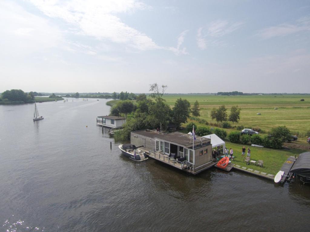 a house boat is docked on a river at Luxe woonboot unieke locatie Friesland Âlde Feanen in De Veenhoop