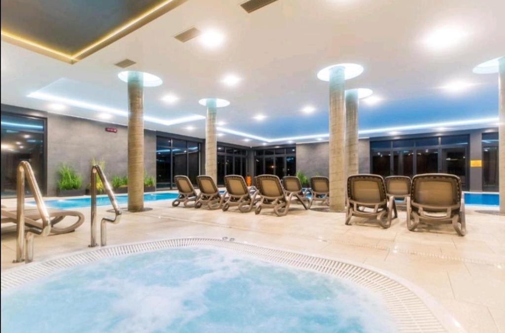 uma piscina num hotel com cadeiras e uma banheira de hidromassagem em Polanki Park u Marty - Basen kryty em Kolobrzeg