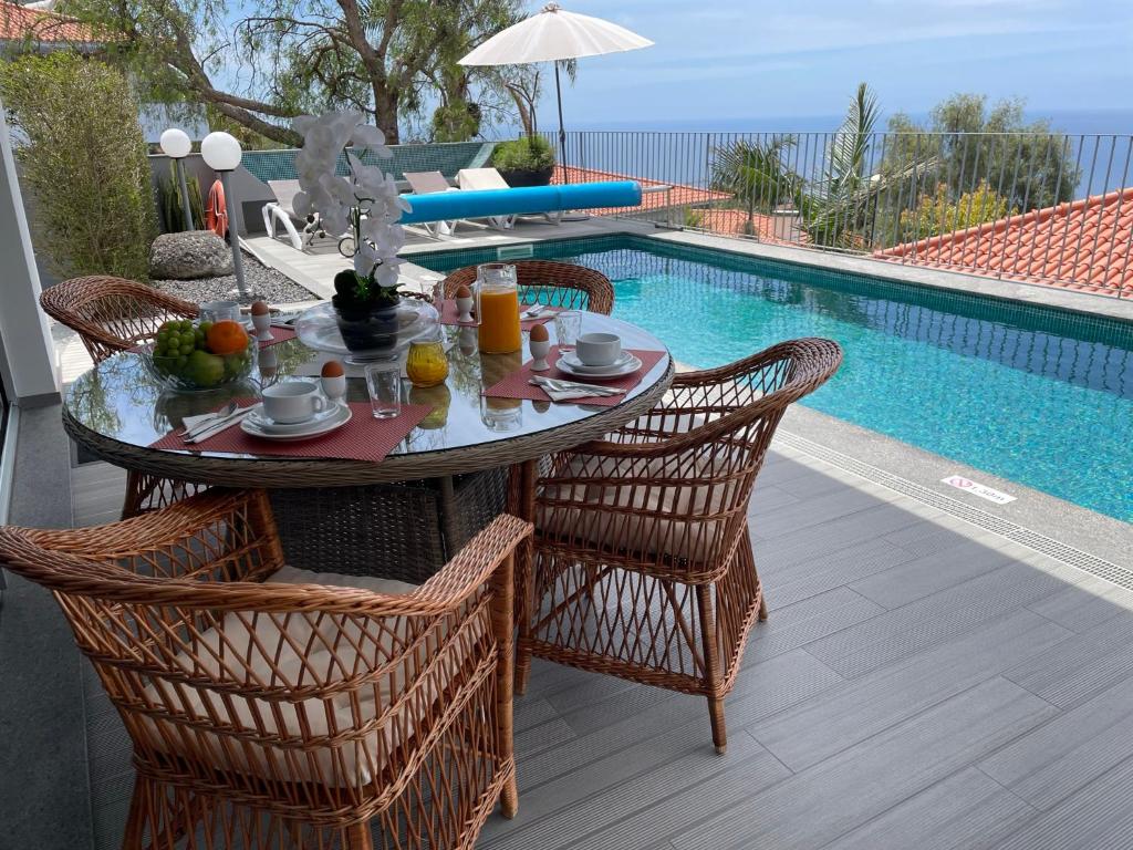 uma mesa com frutas ao lado de uma piscina em Vila Inês - Beautiful 2 bedroom villa with private pool and stunning views of the Atlantic Ocean em Arco da Calheta