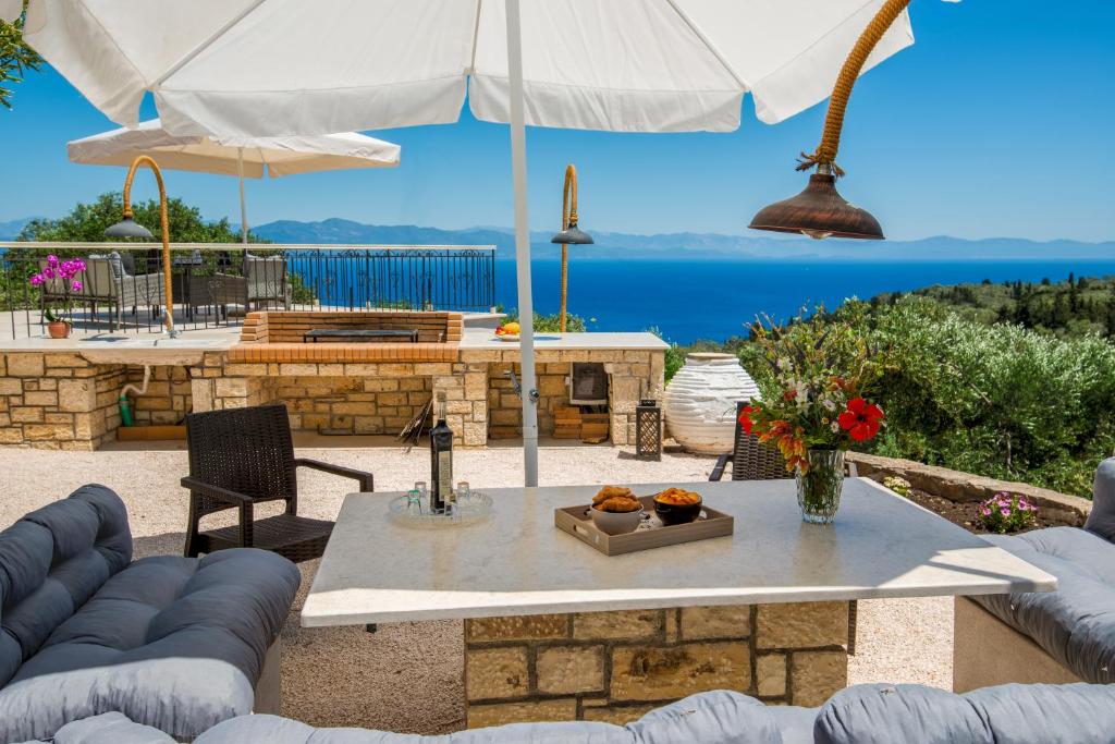a patio with a table and an umbrella at Romanatika Villa Paxos by Dandelion Villas in Gaios